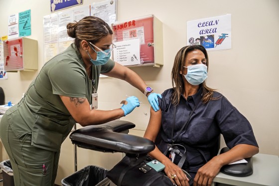 A nurse vaccinates Pri DeSilva with a fourth Pfizer Covid-19 vaccine booster at the Dr. Kenneth Williams Health Center in Los Angeles on Nov. 1, 2022. 
