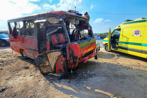 Egyptian emergency services gather near a damaged minibus that was pulled out of a water canal following a crash in al-Dayris village, Egypt