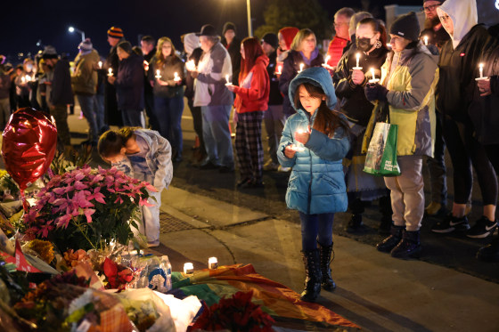 People hold a vigil at a makeshift memorial near Club Q on Nov. 20, 2022, in Colorado Springs, Colo.