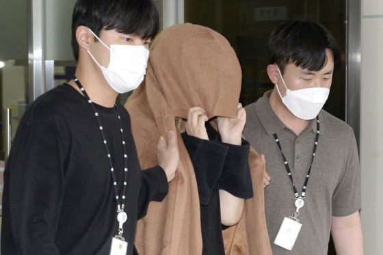 A woman, center, leaves to the Seoul Central District Prosecutors' Office at Ulsan Jungbu police station in Ulsan, South Korea, on Sept. 15, 2022. A South Korean court has approved the extradition of the 42-year-old woman facing murder charges in New Zealand over her possible connection to the bodies of two long-dead children found abandoned in suitcases in August. The Seoul High Court said Friday, Nov. 11, its decision came after the unidentified woman agreed to be sent back to New Zealand.