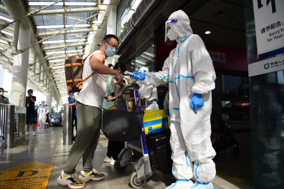 SANYA, CHINA - AUGUST 11: A health worker checks the body temperature of a tourist at Sanya Phoenix International Airport on August 11, 2022 in Sanya, Hainan Province of China. As of 4 am on Thursday, 2,156 stranded tourists due to the latest COVID-19 resurgence in Sanya had departed for home. (Photo by VCG/VCG via Getty Images)