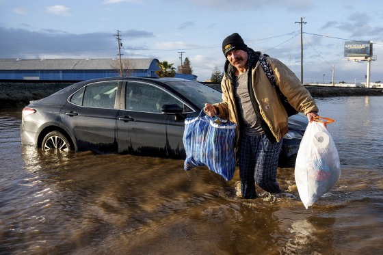 Jesus Torres carries belongings from his flooded home in Merced, Calif.