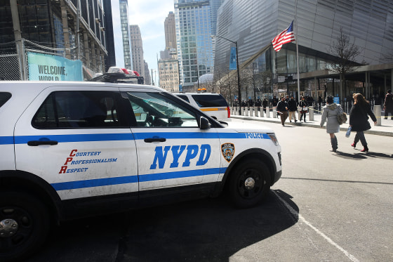 Pedestrians walk past a NYPD vehicle parked in front of One World Trade