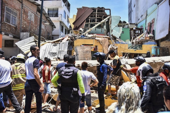 Image: Residents and rescue workers stand in front of buildings brought down by an earthquake that shook Machala, Ecuador, on March 18, 2023.