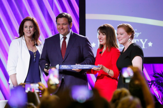 Tiffany Justice, Tina Descovich and Ron DeSantis on stage. 

