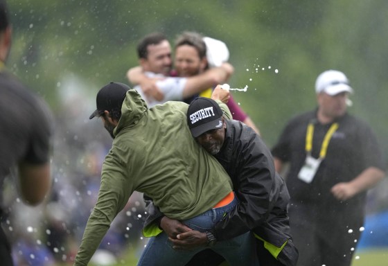 Adam Hadwin, left, is stopped by a security guard while he tries to celebrate with Nick Taylor in Toronto