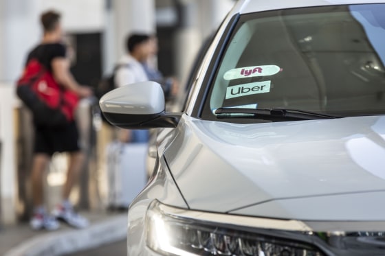 Lyft Inc. and Uber Technologies Inc. signage are displayed on the windshield of a vehicle at Los Angeles International Airport in Los Angeles