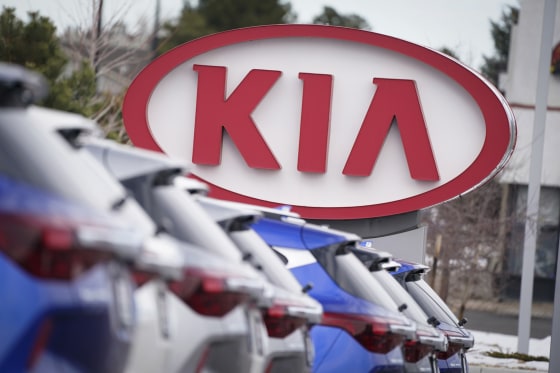 The company logo hangs over a row of cars a Kia dealership in 2020.
