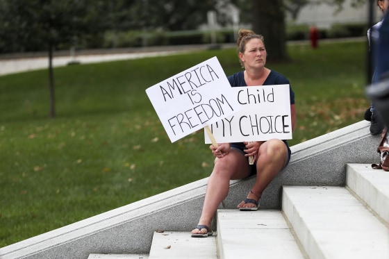 A protester holds signs at a Moms for Liberty rally at the state Capitol in Harrisburg, Pennsylvania on October 9, 2021. About 100 people attended the rally to protest mask and vaccine mandates.