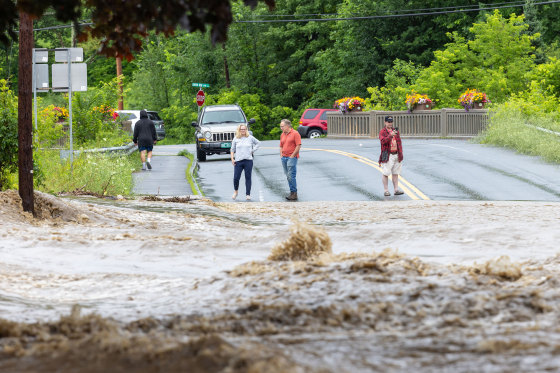Onlookers check out a flooded road on July 10, 2023 in Chester, Vermont. Torrential rain and flooding has affected millions of people from Vermont south to North Carolina.