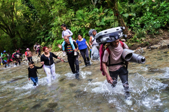 Migrants from Ecuador, Haiti and Nigeria, walk through the river on November 20, 2022 in Darién Gap, Colombia.