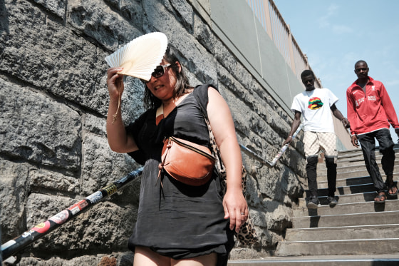 A woman shades herself from the sun as she tries to keep cool along the Brooklyn Bridge during a heat wave on July 27, 2023 in Brooklyn, N.Y.