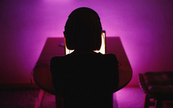 Image: Rear view of woman on laptop late at night
