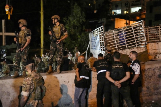Lebanese soldiers stand guard next to an overturned truck in the Christian town of Kahaleh on Aug. 9, 2023.