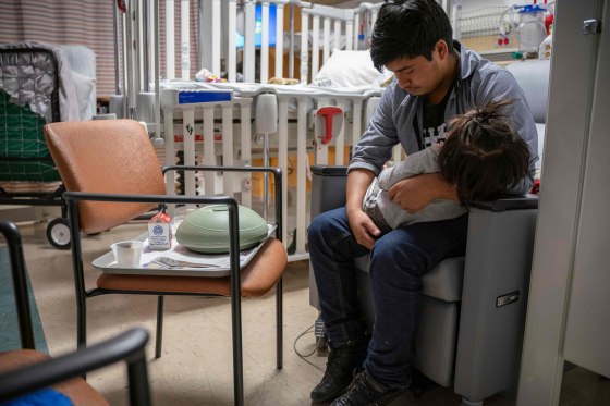 A man holds his sick daughter while at a pediatric intensive care unit