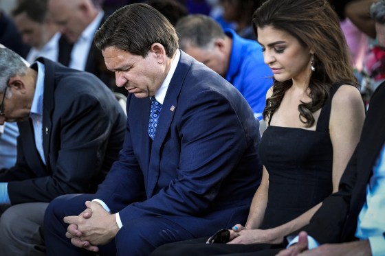 Image: Florida Gov. Ron DeSantis, center and his wife Casey, right, bow their heads during a prayer at a vigil for the victims of Saturday's mass shooting on Aug. 27, 2023, in Jacksonville, Fla.