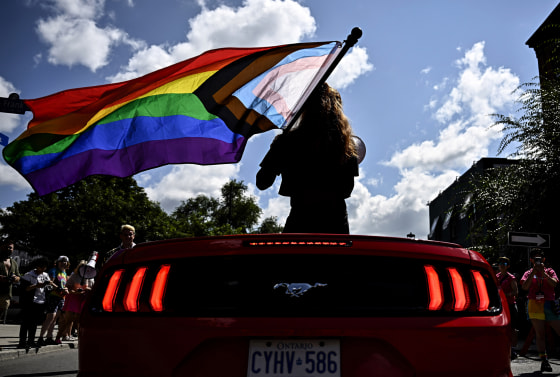 Parade grand marshal Fae Johnstone waves a Pride flag from a convertible during the Capital Pride Parade in Ottawa, Ontario, Canada on Aug. 27, 2023.