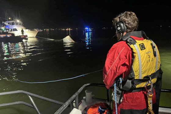 A member of the Islip Fire Department looks at the hull of boat that overturned after a boating crash Sunday night, Sept. 4, 2023, between two vessels on the Great South Bay off Long Island in New York.