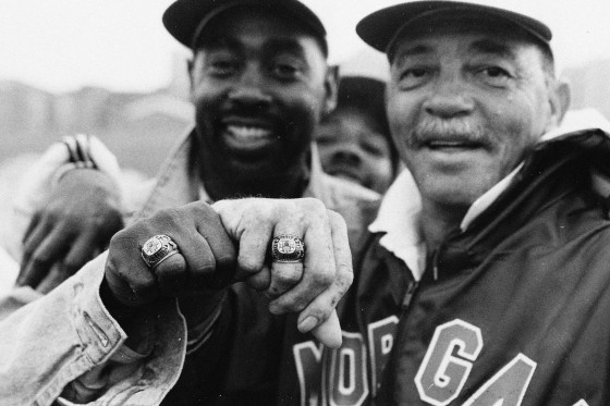 Two alumni pose for a photo showing their school ring.
