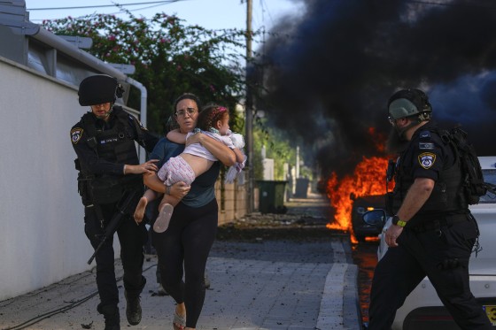 Police officers evacuate a woman and a child from a site hit by a rocket fired from the Gaza Strip