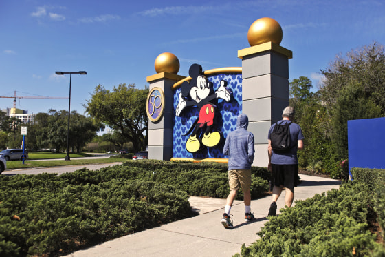 People walk past the entrance to Walt Disney World in Orland