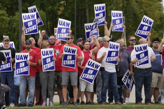 United Auto Workers members hold picket signs near a General Motors assembly plant in Delta Township, Mich., on Sept. 29, 2023.