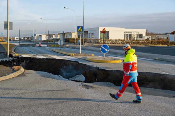 A member of the emergency services walks near a crack cutting across the main road in Grindavik, Iceland on Nov. 13, following earthquakes. 