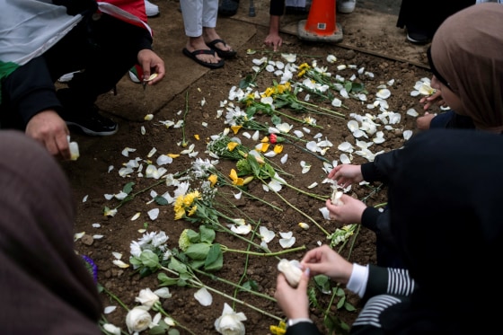 Image: Mourners place flowers at the grave of Wadea Al-Fayoume