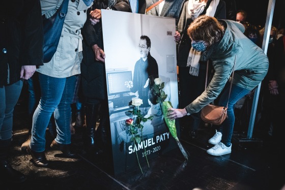 Relatives and colleagues gather around a portrait of Samuel Paty.