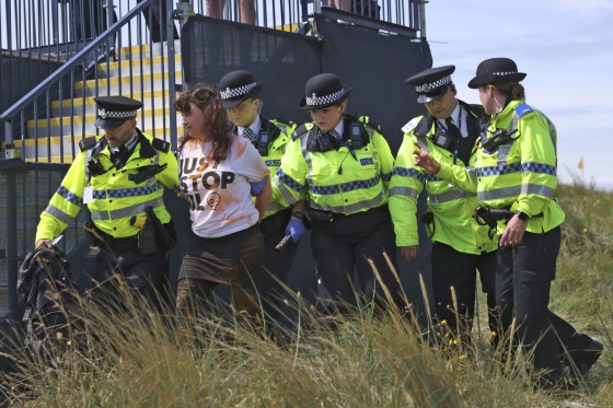 A "Just Stop Oil" protester is led away by police and security at the British Open Golf Championships at the Royal Liverpool Golf Club on July 21, 2023.