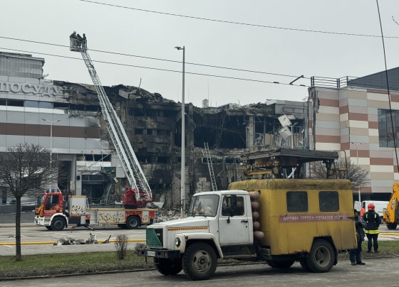 Firefighters and municipal employees work at the site of a rocket attack in Dnipro.