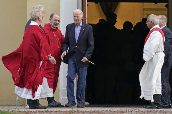 President Joe Biden greets clergy members while carrying a palm branch as he leaves St. Joseph on the Brandywine Catholic Church in Wilmington, Del., on March 23, 2024.