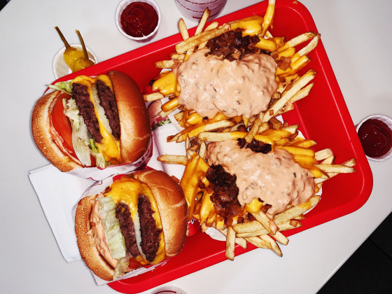 Double cheeseburgers and cheese fries on a tray in fast food restaurant