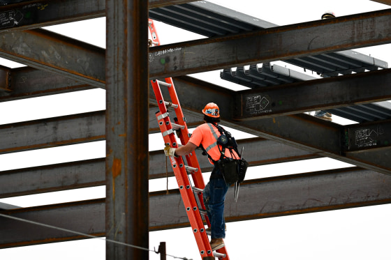 A construction worker climbs a ladder.