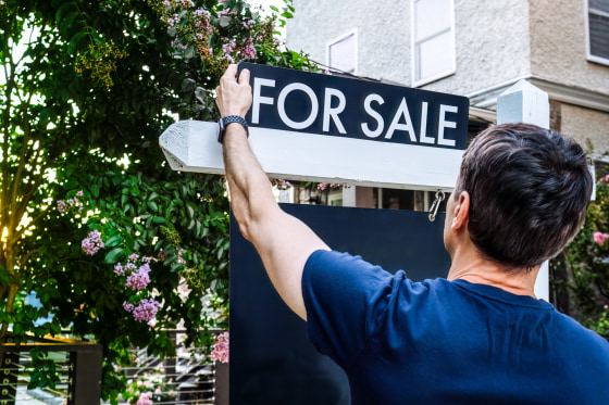 Real Estate Agent Adjusts For Sale Sign in Front Yard