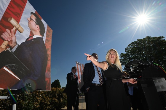 Marjorie Taylor Greene points to a photo of Mike Johnson holding a gavel.