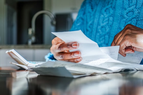 Person reviews receipts at kitchen table