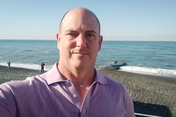 A selfie of John Mark Dougan at the beach with the ocean in the background