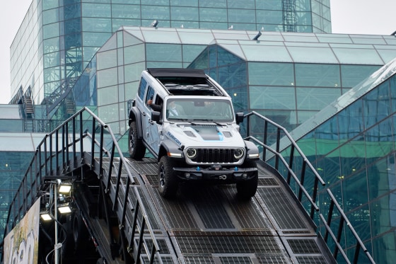 A 2024 Jeep Wrangler 4xe Rubicon plug-in hybrid SUV navigates an obstacle course