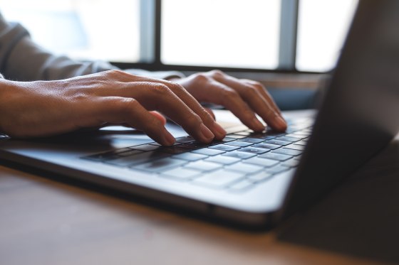 Closeup image of a woman working and typing on laptop computer keyboard on the table