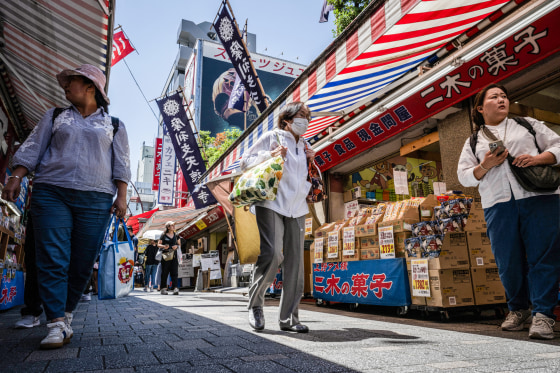 People walk through a shopping district outdoors