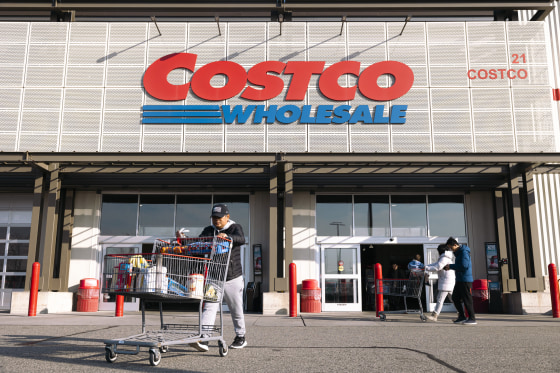 A Costco storefront with shoppers wheeling cart