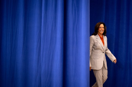 Kamala Harris walks through a blue curtain