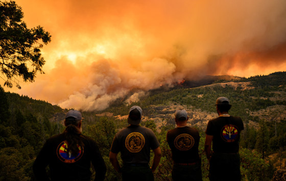 Firefighters watch as flames and smoke move through a valley in the Forest Ranch area of Butte County near Chico, Calif.