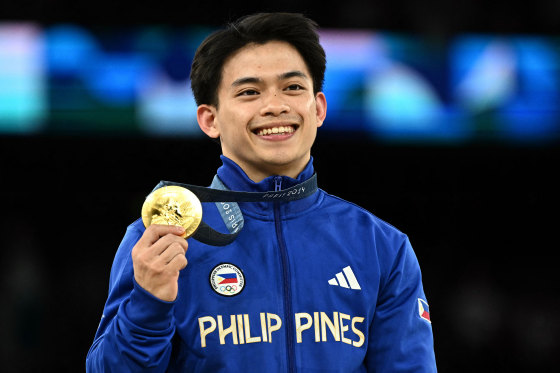 Carlos Yulo smiles while holding up his medal