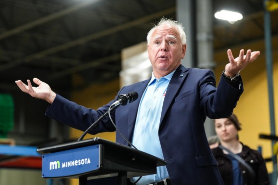 Tim Walz speaks at a podium, raises his hands