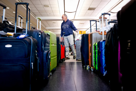 A traveler searches for a suitcase in a baggage holding area