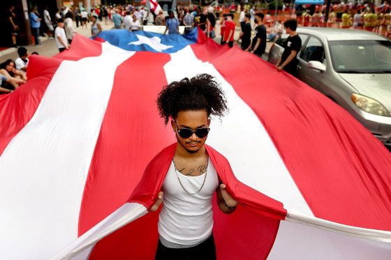 A participant helps carry the flag of Puerto Rico