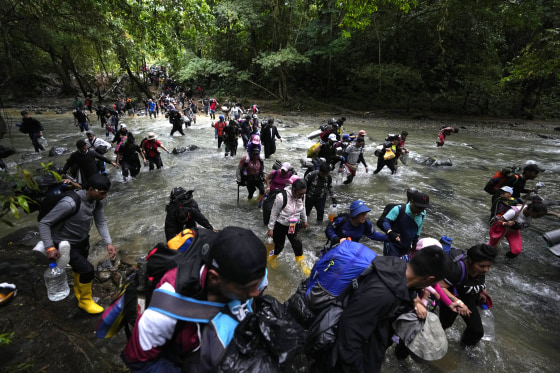 Migrants, mostly Venezuelans, cross a river during their journey through the Darien Gap from Colombia into Panama on Oct. 15, 2022.