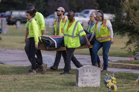 Researchers and burial oversight committee member Brenda Alford carry the first set of remains exhumed from the latest dig site in Oaklawn Cemetery to an on-site lab for further examination in Tulsa, Okla., on Sept. 13, 2023.